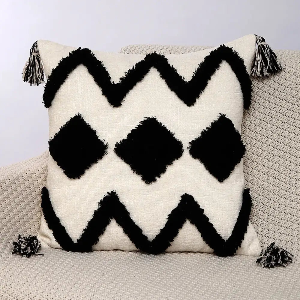 Cream-colored pillow covers with black fringe zigzag and diamond patterns and tassels in decorbites geometric chenille embroidered design
