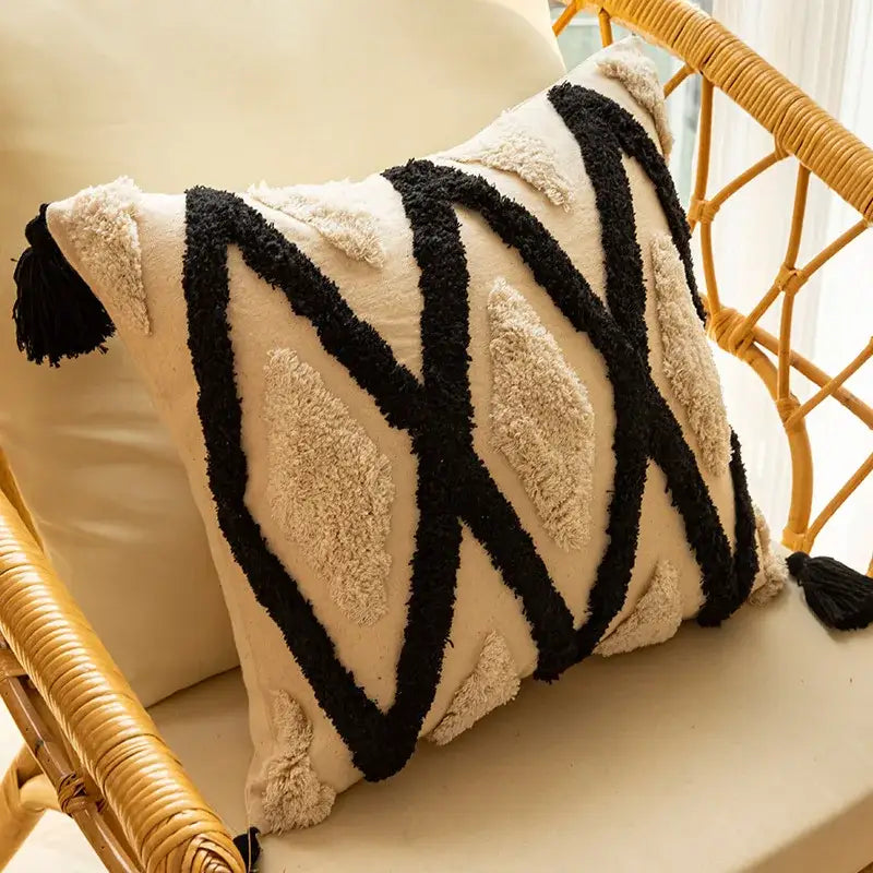 Cream-colored pillow covers with black and beige geometric chenille embroidered patterns and tassels for living room decor