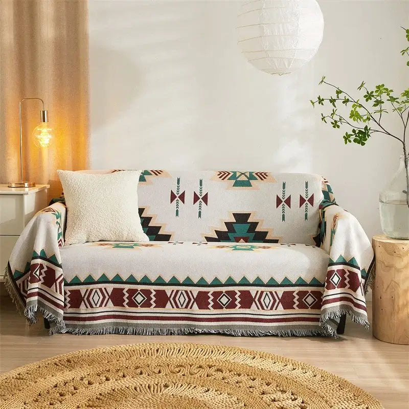 A cozy white sofa with a decorbites boho chenille throw blanket featuring bold maroon and teal geometric patterns