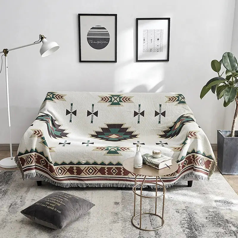 A cream-colored decorbites boho chenille throw blanket with geometric tribal patterns and fringed edges for living room decor