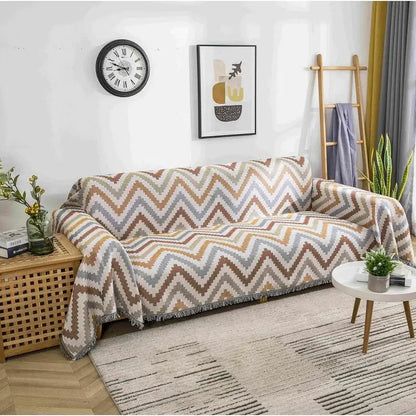 A cozy boho chenille woven throw blanket with a multitone zigzag pattern in beige brown and gray and fringed edges