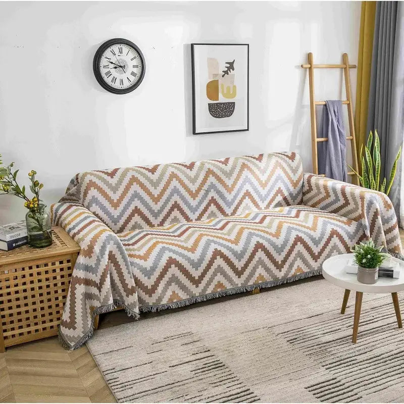 A cozy boho chenille woven throw blanket with a multitone zigzag pattern in beige brown and gray and fringed edges