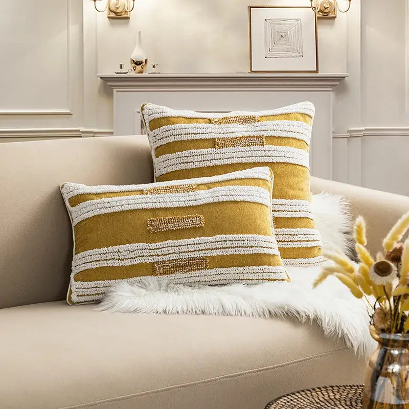 Two mustard yellow and white textured cushion covers with embroidered accents on beige sofa for decorbites boho loop tufte decor