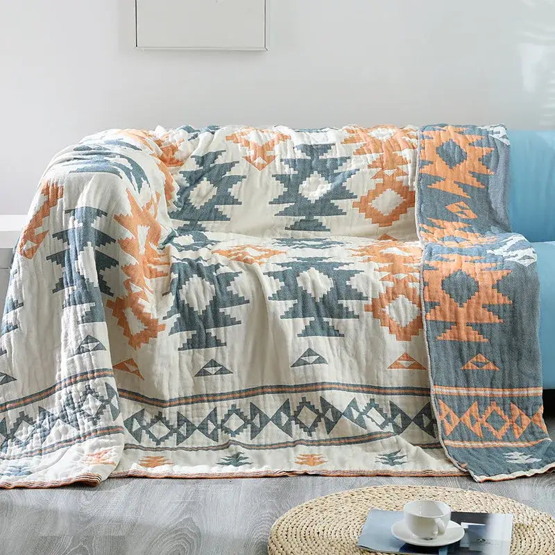 A cozy decorbites boho cotton throw blanket with geometric tribal pattern in orange, blue, and cream for sofa decor