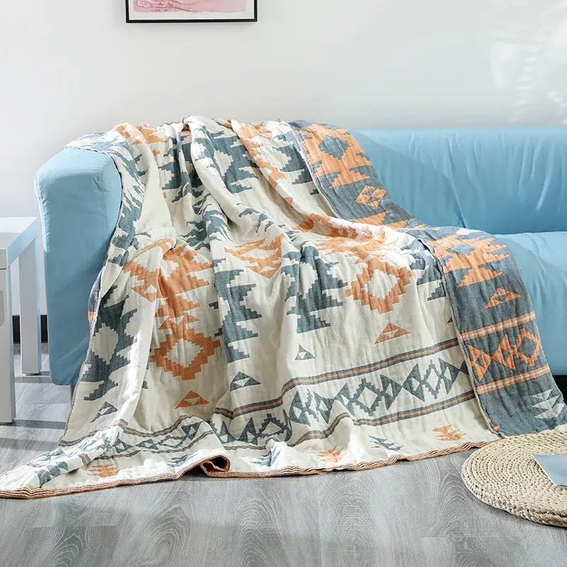 A cream-colored decorbites boho cotton throw blanket with orange and blue geometric patterns for sofa decor