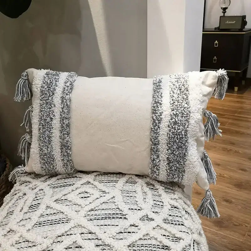 Cream-colored boho geometric tufted cushion cover with textured gray and white woven stripes and tassel decorbites design