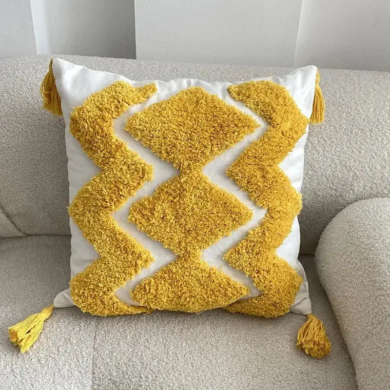 A vibrant yellow and white boho geometric tufted cushion cover with fluffy tassels for living room decorbites decor