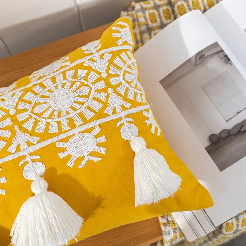 Vibrant yellow boho gold embroidered cotton pillow cover with intricate white embroidery and matching tassel decorbites boho gold decor