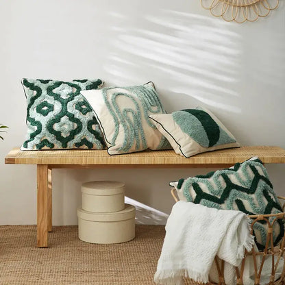 Three textured green and cream cushion covers with embroidered geometric patterns on a woven bench for decorbites blue tufted decor