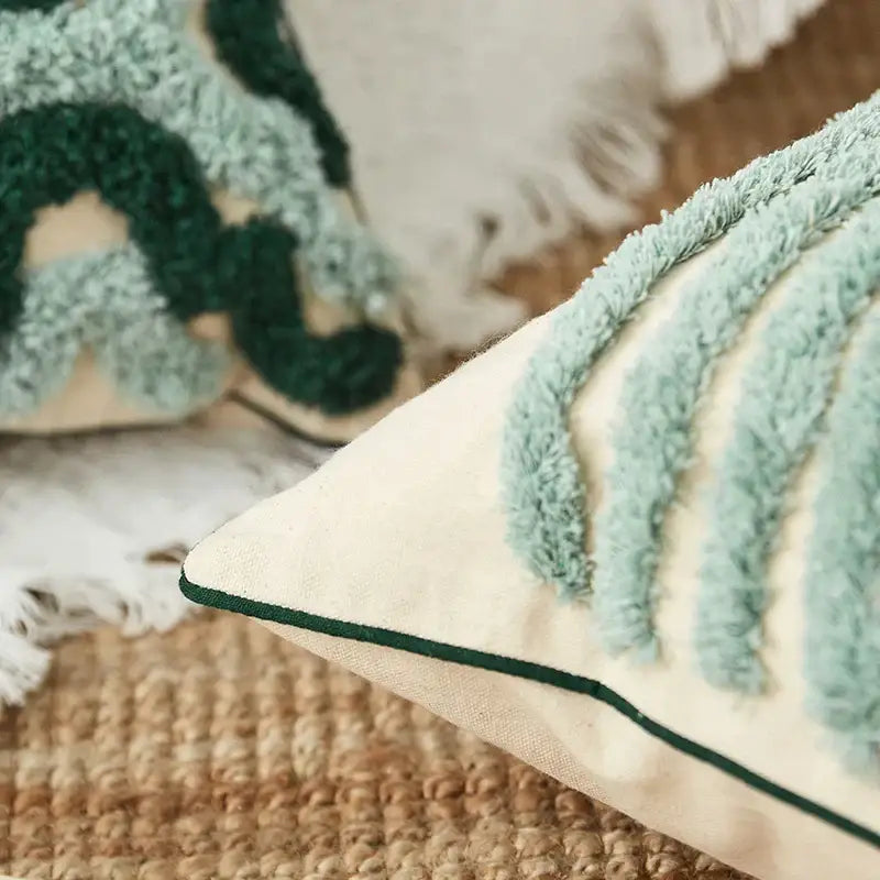 Cream-colored cushion cover with blue tufted geometric leaf patterns and dark green stitched border for decorbites decorbites blue tufted