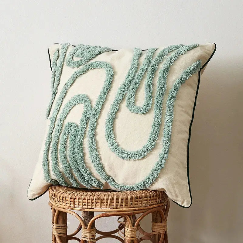 Cream-colored cushion cover with light blue textured yarn swirls and black trim for boho green decorbites blue tufted style