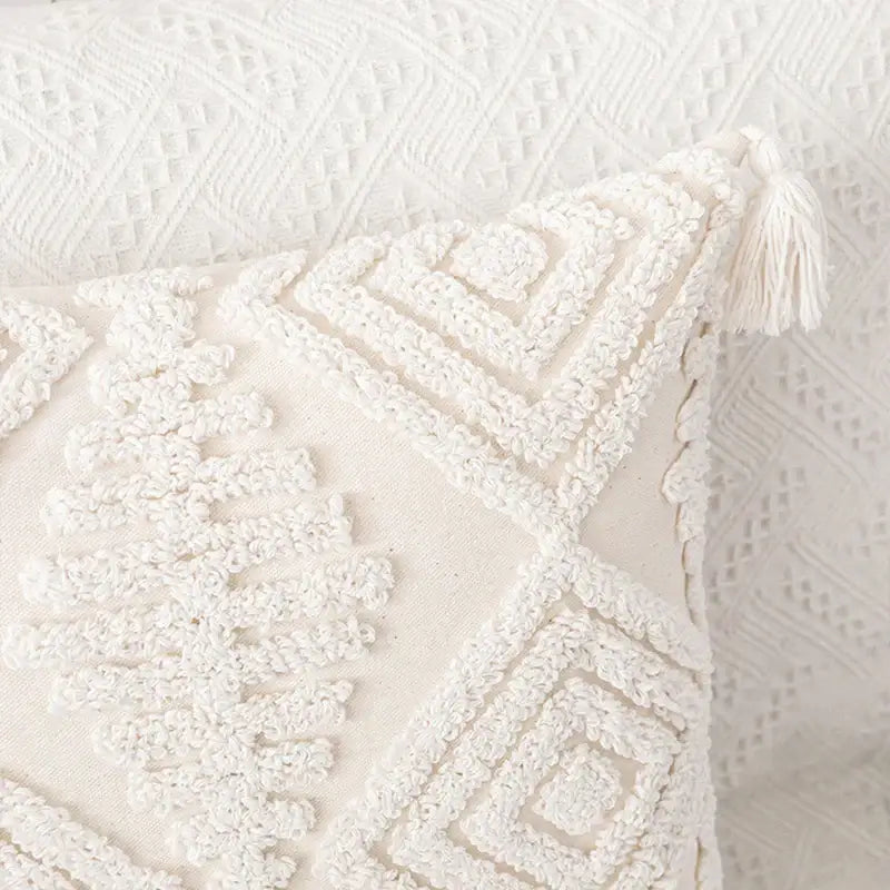 Cream-colored boho ivory cotton loop cushion cover with textured embroidered geometric patterns and tassel accent for decorbites