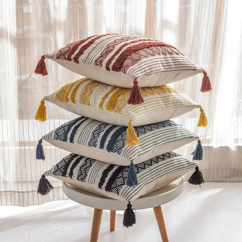 Stack of four woven geometric boho jacquard cushion covers with tassels in navy blue and mustard yellow decorbites style