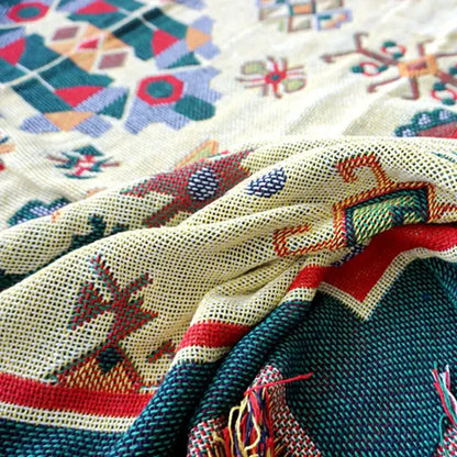 A boho jacquard knitted throw blanket with vibrant geometric patterns in red green blue and orange on a cream base