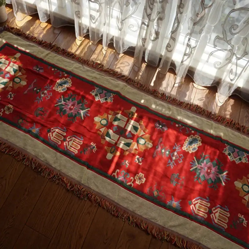 A vibrant red decorbites boho jacquard knitted throw blanket with intricate floral embroidery and fringed edges