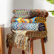 Stack of colorful boho knitted striped throws with zigzag pattern and fringed edges for living room decorbites decor