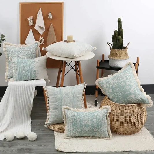 A collection of boho light blue and white patterned pillow covers with fringed edges displayed on wooden floor decorbites green tassel pillow