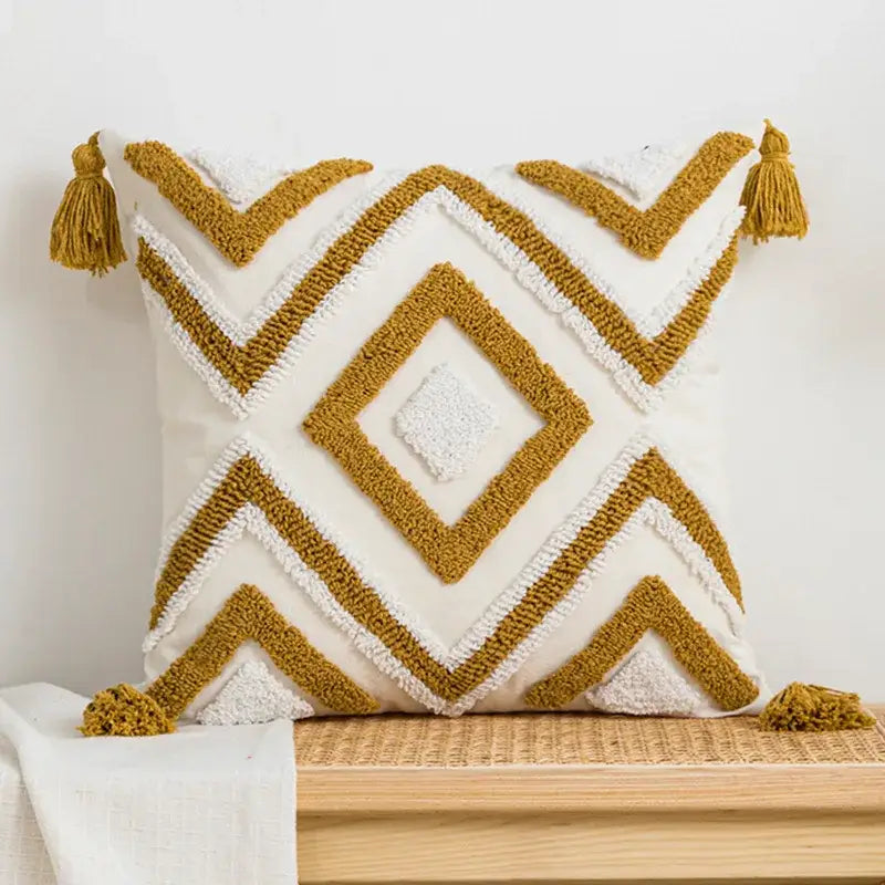 A cream-colored decorbites boho loop tufted pillow cover with mustard-yellow geometric patterns and tassels for bedroom decor