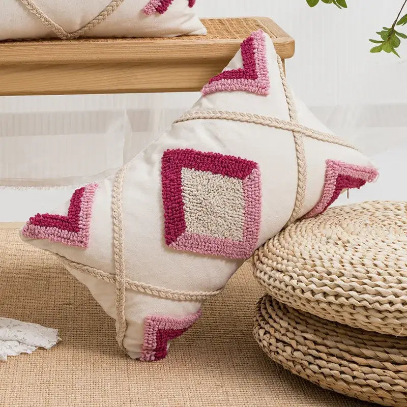 Cream-colored pillow cover with pink beige geometric embroidery and braided rope detailing boho loop tufted decorbites