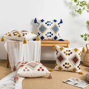 White cushion pillow cover with boho loop tufted geometric patterns in blue brown yellow yarns and tassel accents