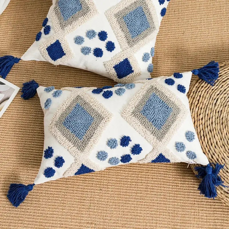 White rectangular pillow cover with blue and gray embroidered geometric patterns and navy tassels by decorbites boho loop tufted