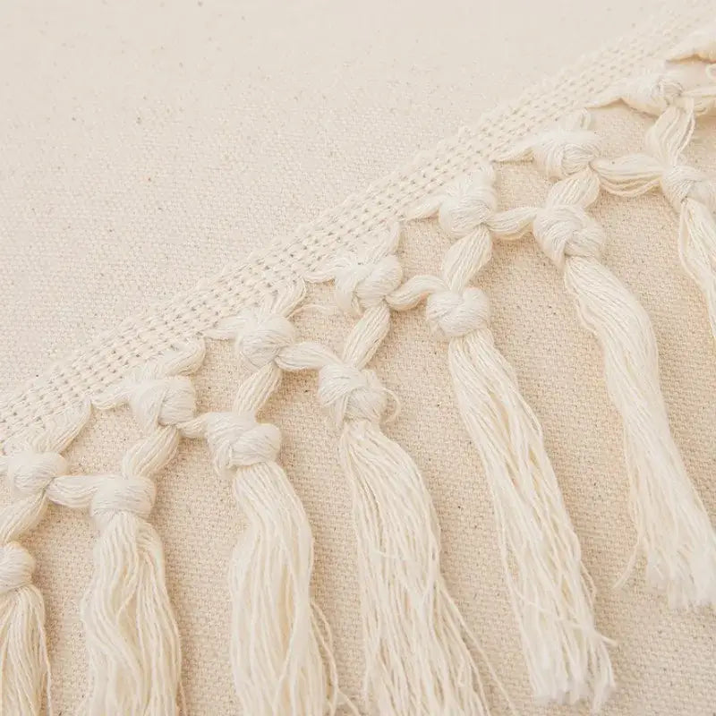 Cream-colored boho macrame woven cushion cover with cotton knotted tassels and fringe for bedroom decor by decorbites