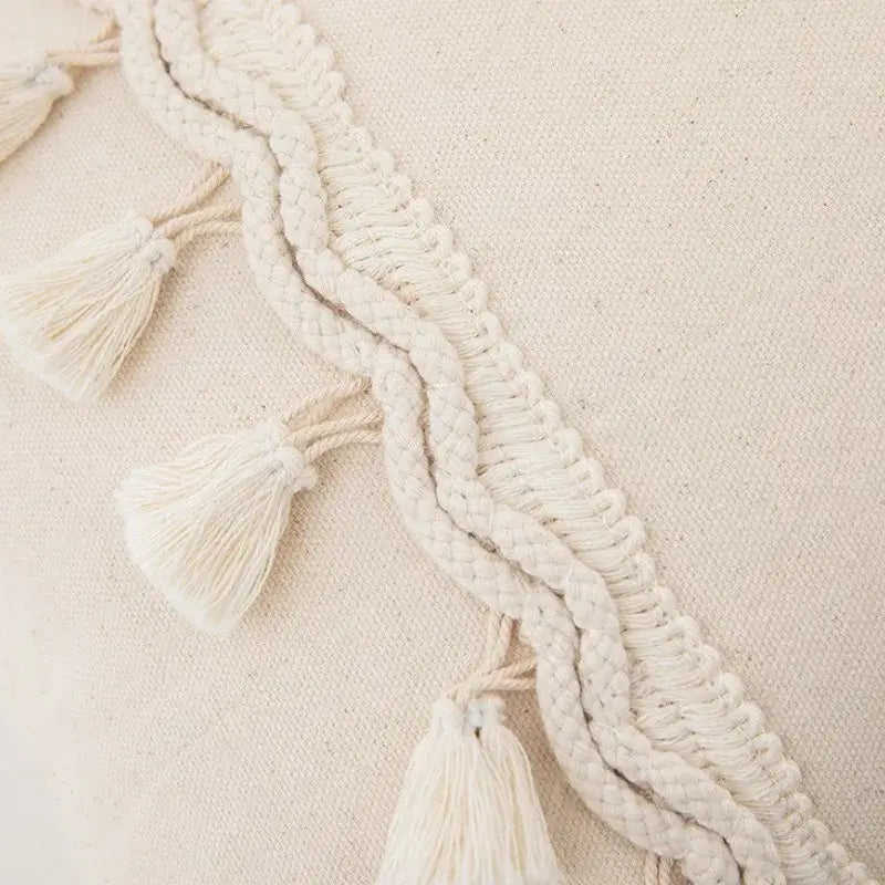 Cream-colored boho macrame woven cotton tassel trim with braided cords and fluffy fringe on decorbites cushion cover