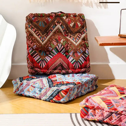 Brown and red geometric-patterned quilted square floor pillow with embroidered details for boho living room seating