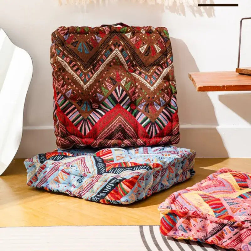 Brown and red geometric-patterned quilted square floor pillow with embroidered details for boho living room seating