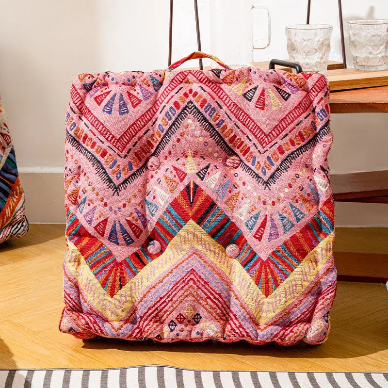 A vibrant pink multicolored geometric square floor pillow with drawstring top and decorative buttons for living room seating