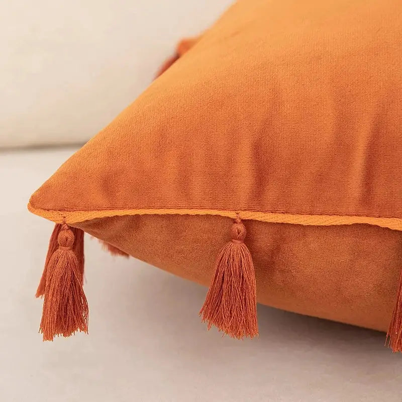 A plush orange velvet tassel fringe pillow cover perfect for boho home decor and living room accents