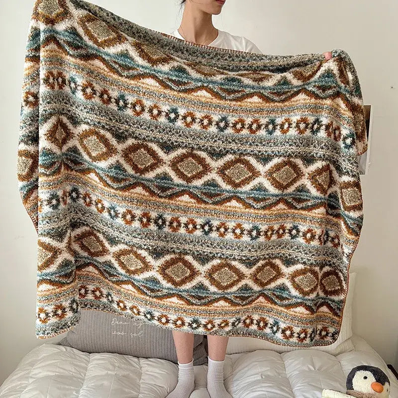 A cozy chunky knit boho printed blanket with earthy geometric pattern in brown teal and cream for bedroom use