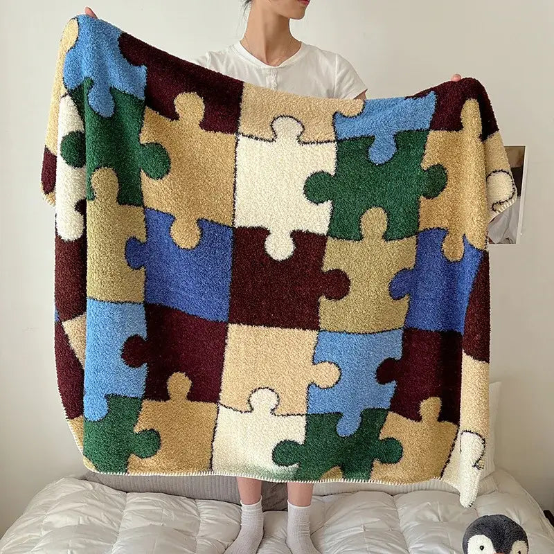 A cozy plush boho printed blanket with vibrant blue green beige and maroon puzzle-piece pattern for bedroom use