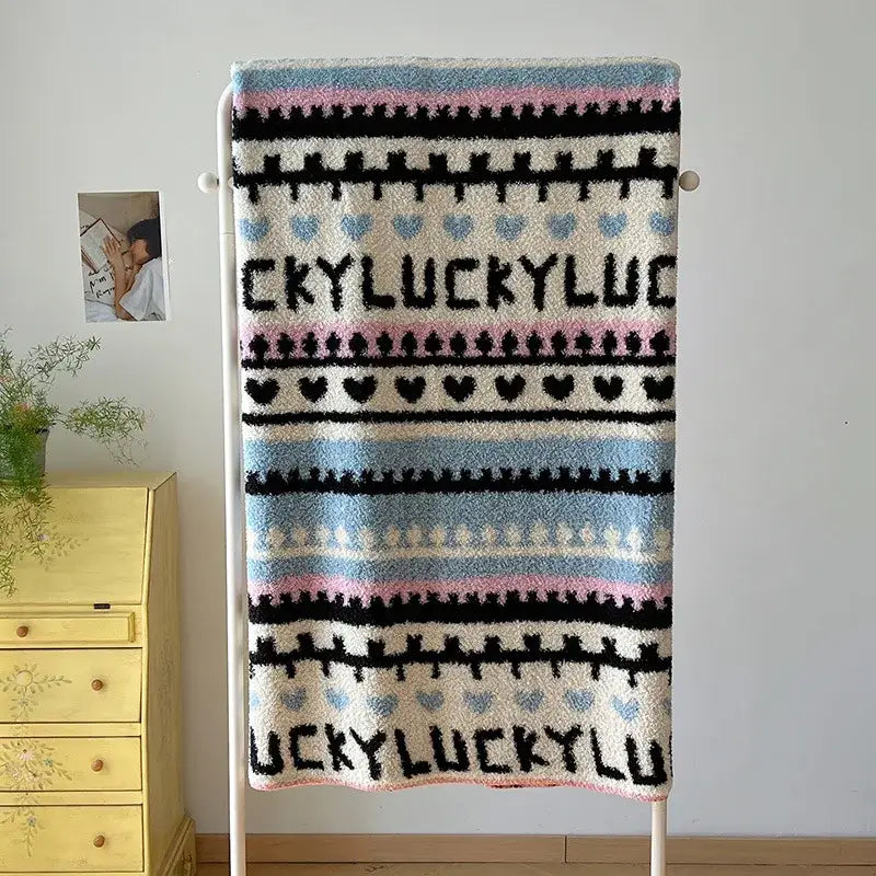 Cozy cream-colored boho printed blanket with black light blue pink stripes heart motifs and lucky text in chunky knit design