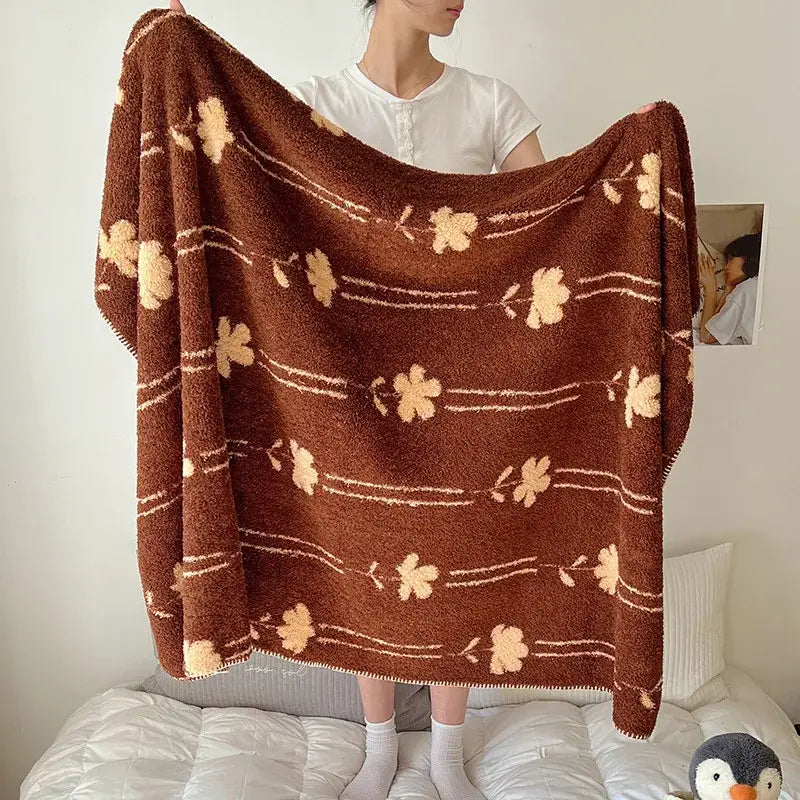 A cozy brown plush boho printed blanket with beige floral patterns and thin white lines, perfect for bedroom use