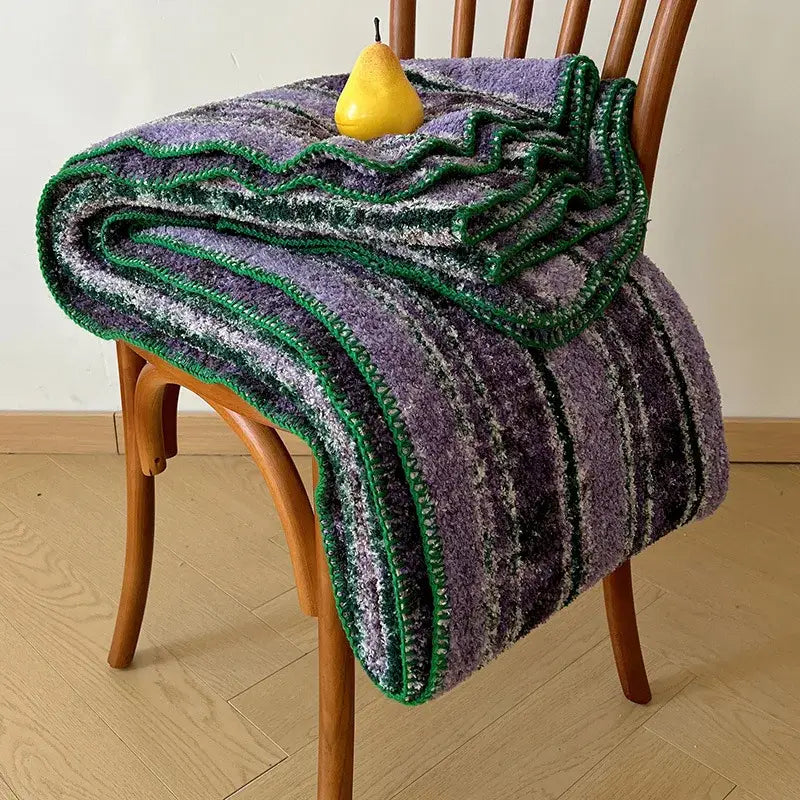 A cozy boho printed blanket in purple and green chunky knit with earthy geometric stripes and a bold green border