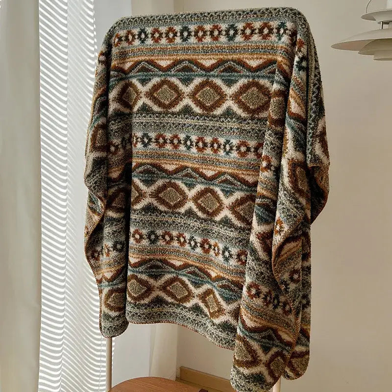 A boho printed chunky knit blanket in earthy brown beige and muted green with a geometric pattern for bedroom use
