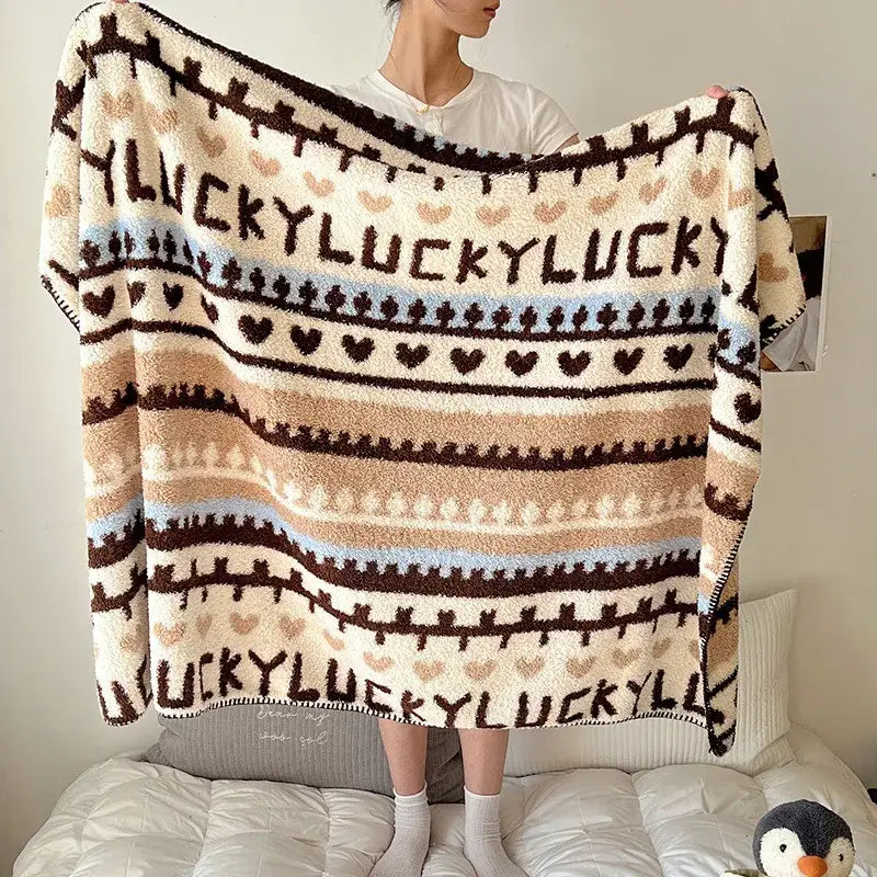 A cozy cream and brown boho printed blanket with lucky text, heart motifs, and striped chunky knit design