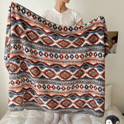 A cozy boho printed blanket with chunky knit and earthy geometric pattern in red blue and cream for bedroom use