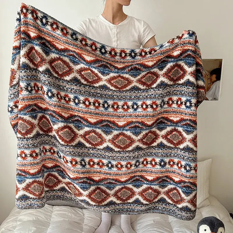 A cozy boho printed blanket with chunky knit and earthy geometric pattern in red blue and cream for bedroom use