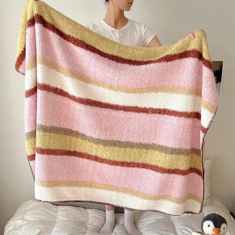 A cozy boho printed blanket with soft pink cream and mustard yellow stripes in chunky knit for bedroom use