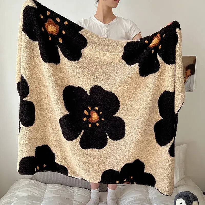 Cream-colored plush boho printed blanket with bold black floral patterns and golden centers for bedroom use