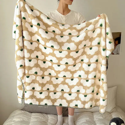 A cream-colored boho printed blanket with soft fluffy texture and white cloud shapes accented by green dots