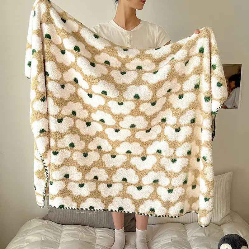 A cream-colored boho printed blanket with soft fluffy texture and white cloud shapes accented by green dots