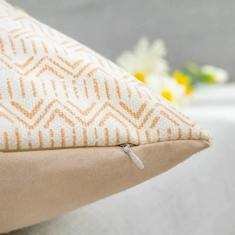 Cream-colored boho style cotton pillow cover with subtle orange geometric pattern and matching zipper closure by decorbites