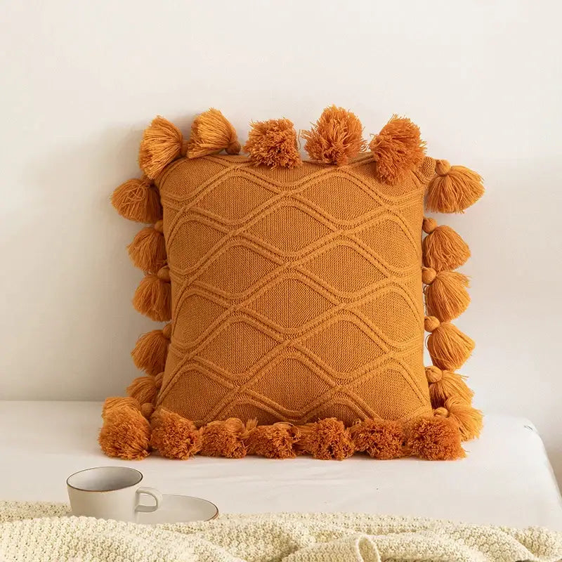 Warm orange knitted throw pillow with diamond pattern and tassels from decorbites boho style ivory cushion cover collection