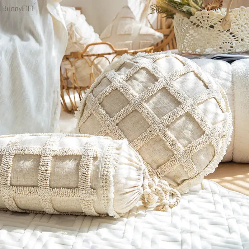 Cream-colored cylindrical bolster cushion cover with woven grid pattern frayed edges and drawstring ties decorbites boho tassel