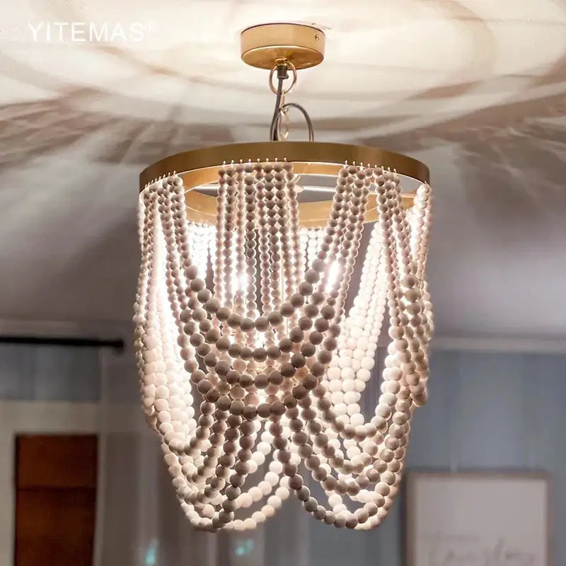 Boho tiered wooden beaded chandelier with white beads and gold-toned frame for dining room lighting