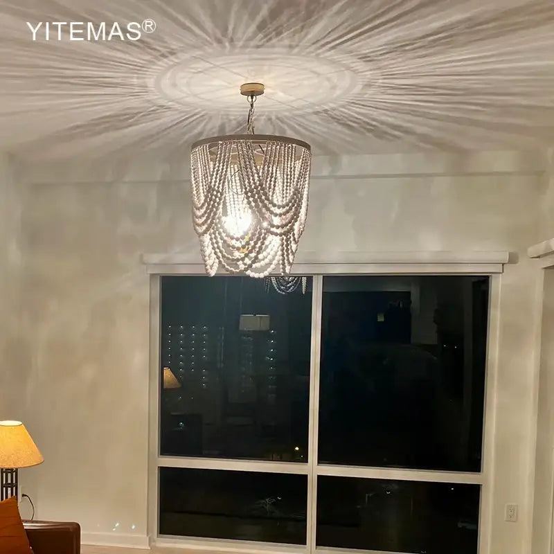 Boho tiered wooden beaded chandelier by yitemas with cascading white beads creating sunburst light pattern for dining room