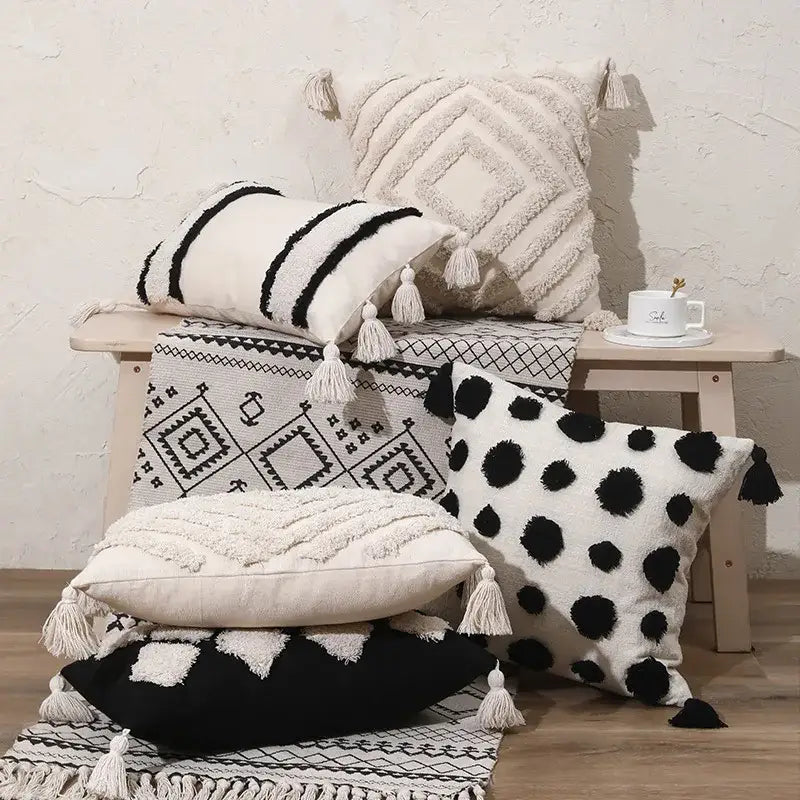 A collection of decorbites boho tufted beige and white pillow cover with black and white patterns and tassel decor